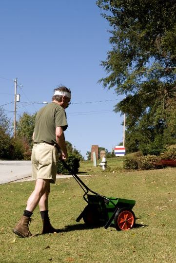 Man applying fertilizer in lawn Matthews Turf Management Augusta GA