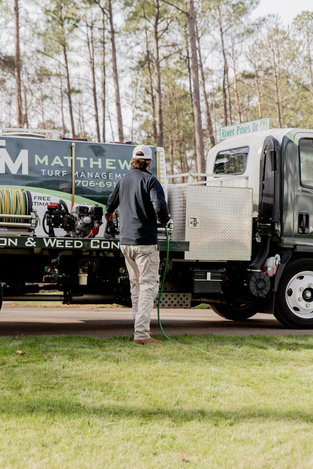 Matthews Turf Management employee with hose next to branded service truck